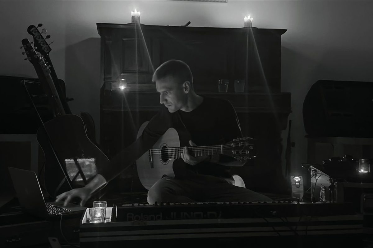 Adam Konieczny gra na gitarze podczas kameralnego koncertu relaksacyjnego przy świecach — zdjęcie czarno-białe